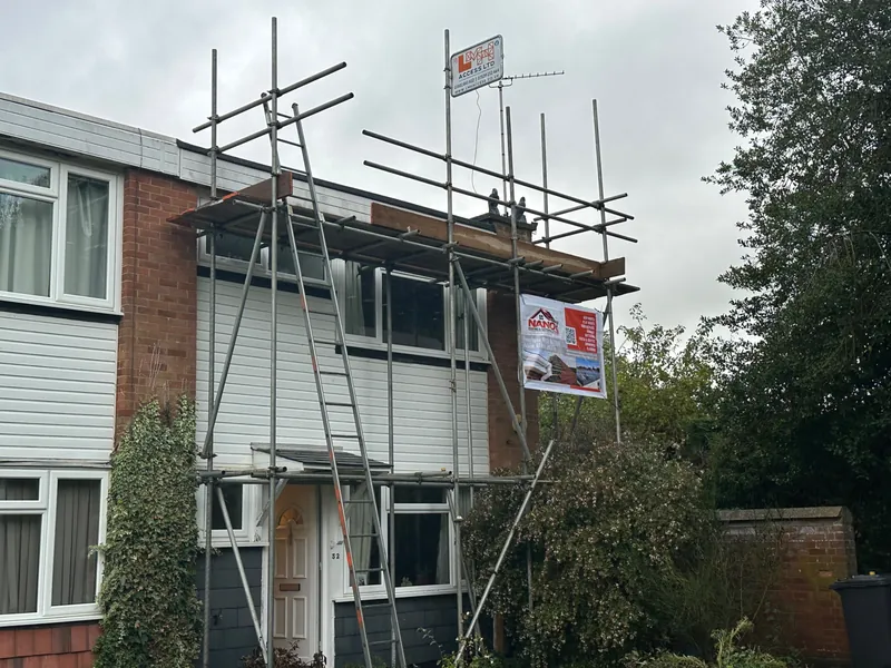 Front of a clad end-terrace house with scaffolding and a ladder up to the roofline and a Nano Roofing & Guttering banner
