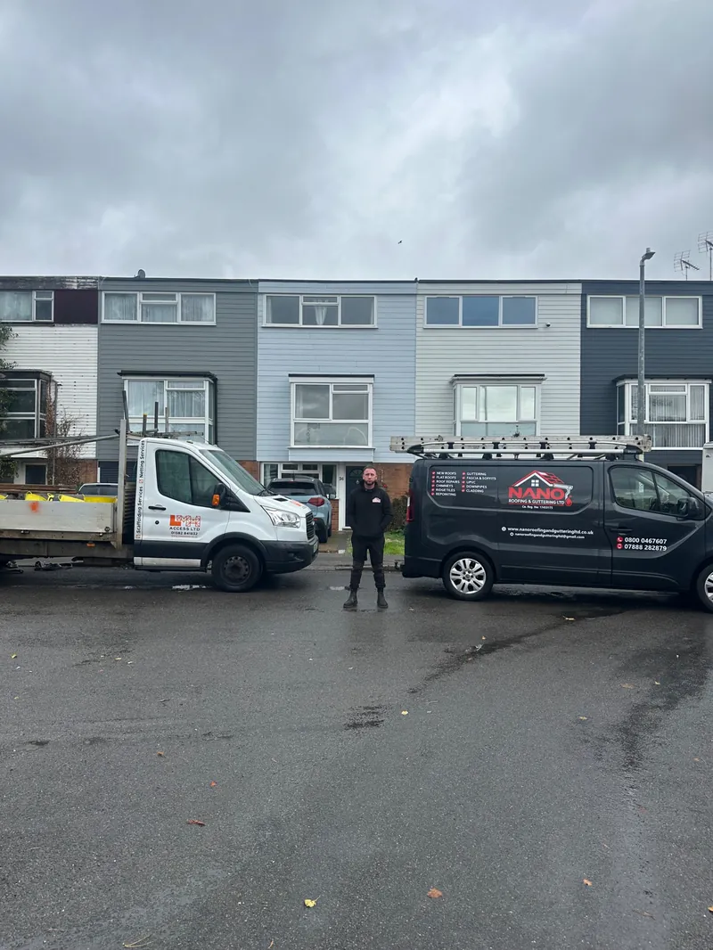 Nano Roofing & Guttering team member standing between the Nano van and a scaffold lorry on a terraced street