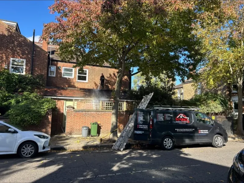 Nano Roofing & Guttering van with a ladder up to a brick house on a tree-lined street