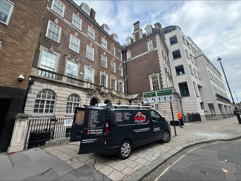Nano Roofing & Guttering van with its rear doors open outside a red brick mansion block