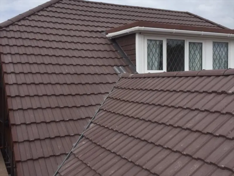 Brown concrete tiled roof around a dormer with leaded windows