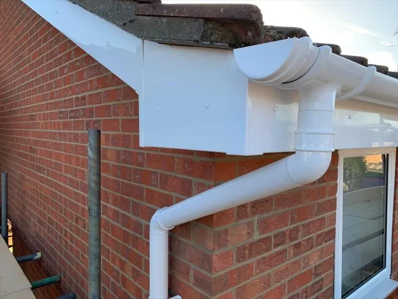White uPVC gutter, box end and downpipe on the corner of a red brick house