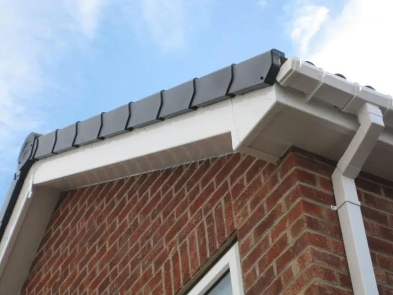 White fascia, soffit and gutter with a downpipe at the eaves of a red brick house