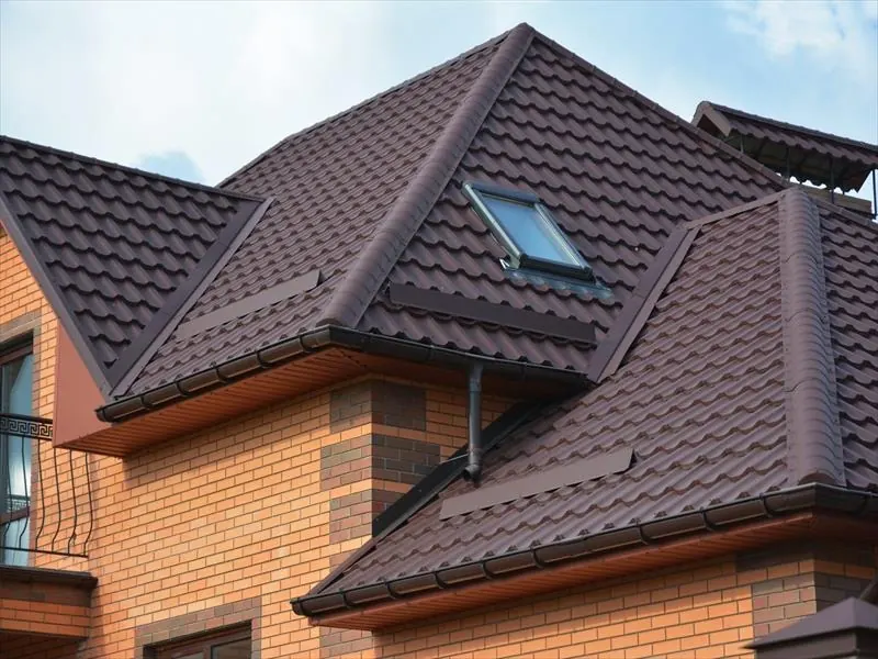 Brown tiled hipped roof with a roof window, dark fascia and guttering