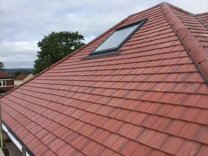 Red tiled pitched roof with a roof window and ridge tiles