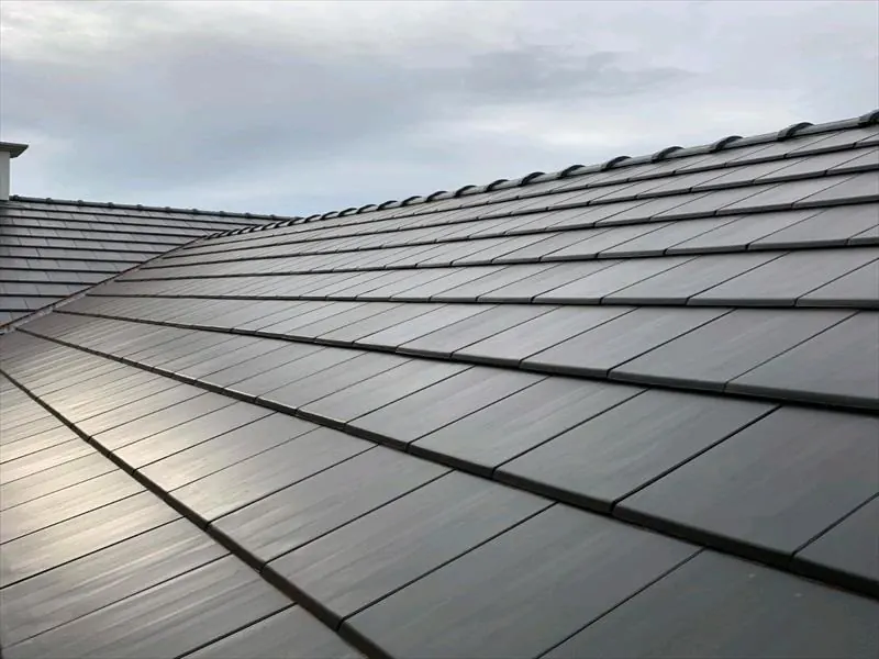 Close view of dark grey slate-effect roof tiles laid in neat courses